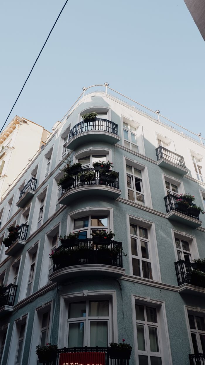 gallery-01 Classical apartment building exterior featuring elegant balconies and glass windows in a low angle view.