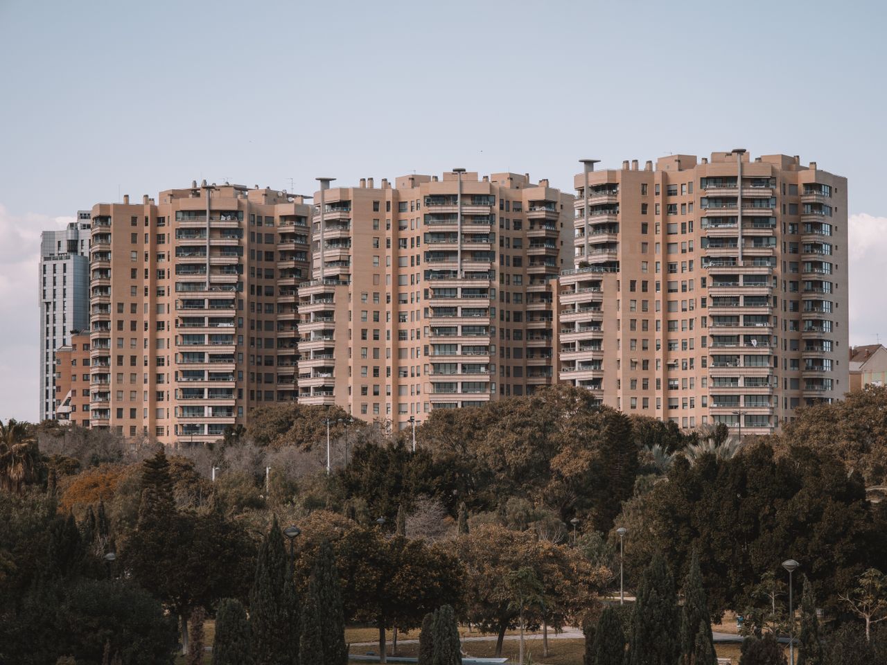 home-img Seventeen-story apartment buildings in Valencia, Spain, with surrounding greenery under a clear sky.